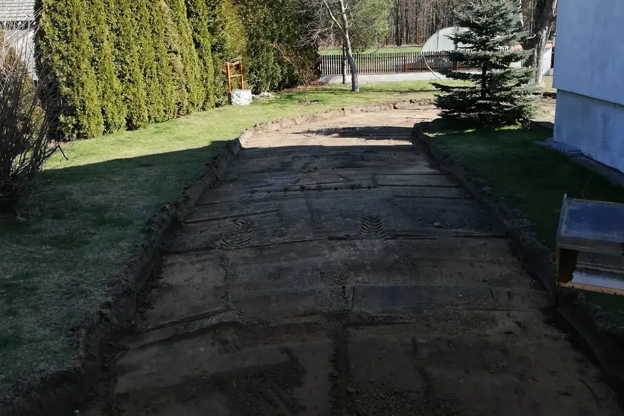 Wykorytowany podjazd przy domu, po bokach trawnik