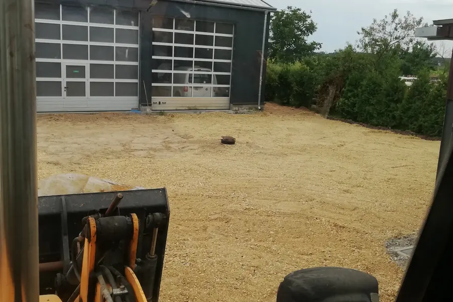 Utwardzony kruszywem plac przed halą, widok z kabiny koparko-ładowarki